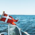 white-flag-boat-floating-top-ocean-blue-sky-daytime