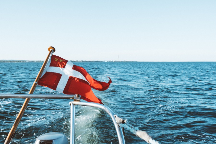white-flag-boat-floating-top-ocean-blue-sky-daytime